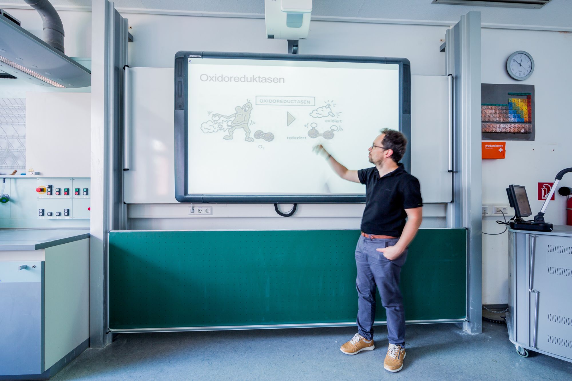 Eine Person steht vor einem Digitalen Whiteboard und zeigt darauf