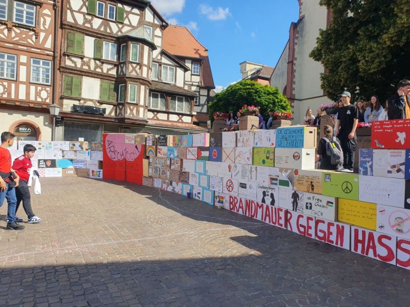 Auf dem Bild sieht man eine Mauer aus Kartons und mehrere Personen