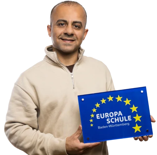 Ein Schüler der ein Schild in der Hand hält und lacht.