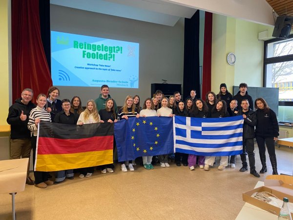 Ein Bild mit einer Menschengruppe wo drei Flaggen hochgehalten werden.